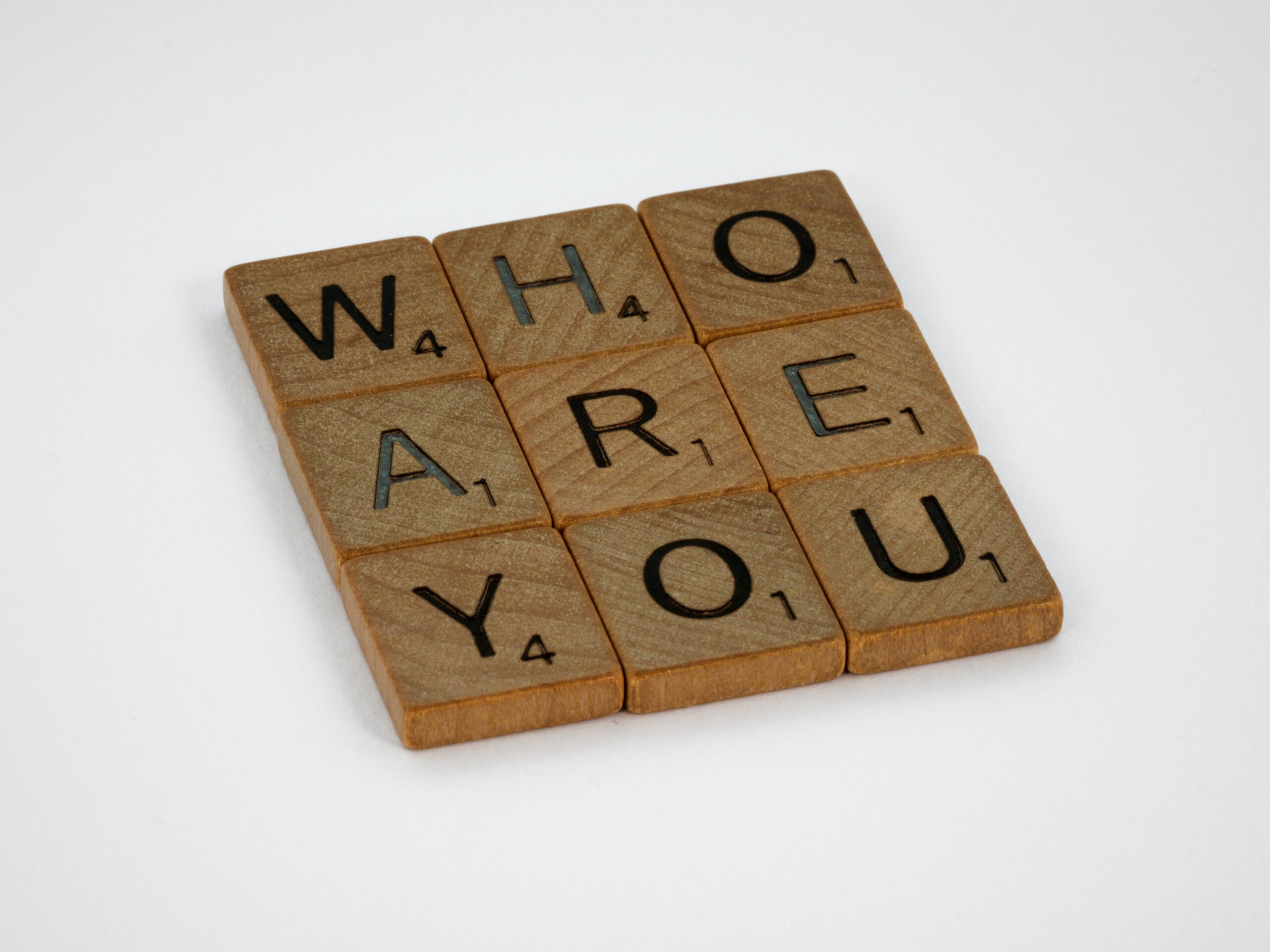 Scrabble letters on wooden tiles depicting the words who are you