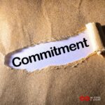 The brown paper wrapping on a box has been peeled back to reveal the word Commitment