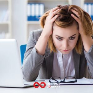 A lady wearing a suit sits at her desk with her head in her hands
