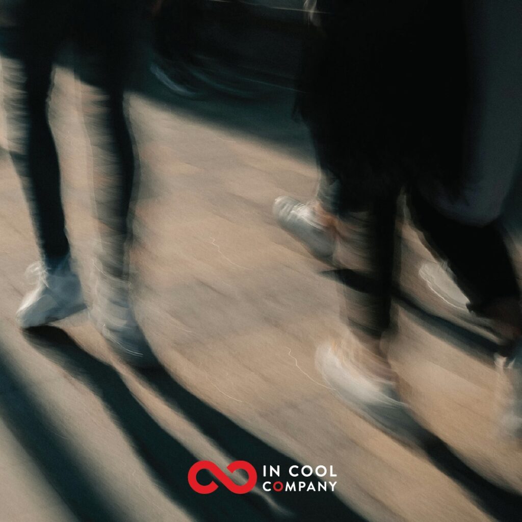 Two pairs of feet are blurred from the speed of walking along a pavement
