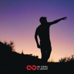 The silhouette of a man pointing into the distance