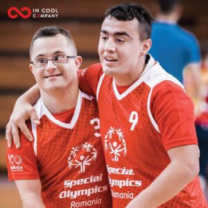 Two males in Romanian sports shirts embrace in a sports hall