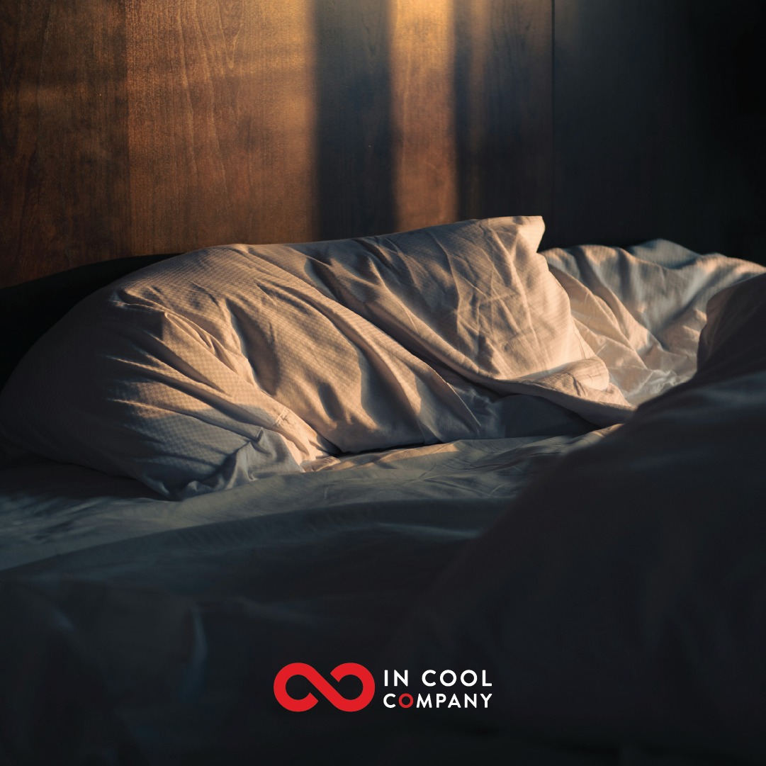 An unmade bed with some morning light shining across it