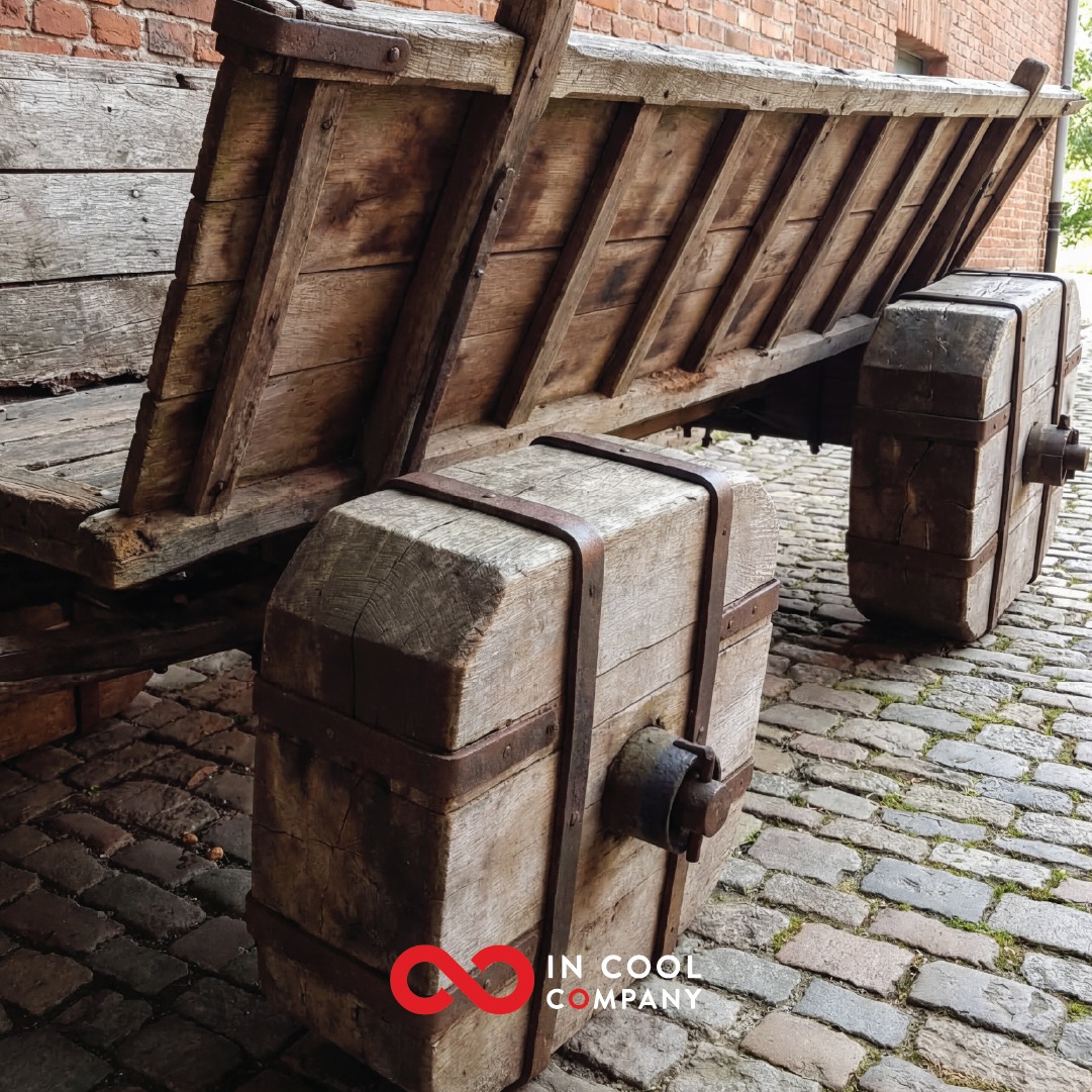 An old wooden coal truck sits on a cobbled path