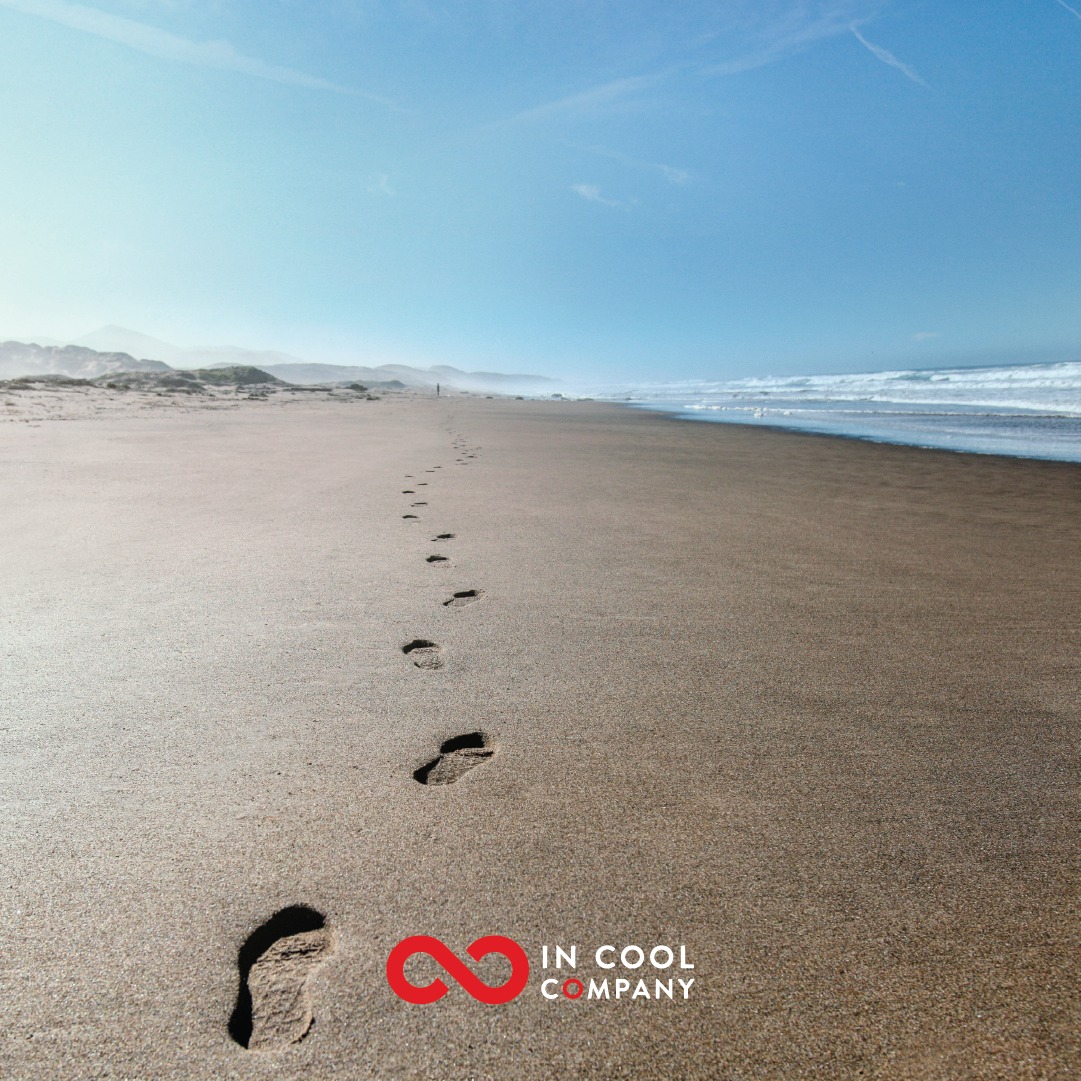 A single line of footprints disappear into the distance on a sandy beach