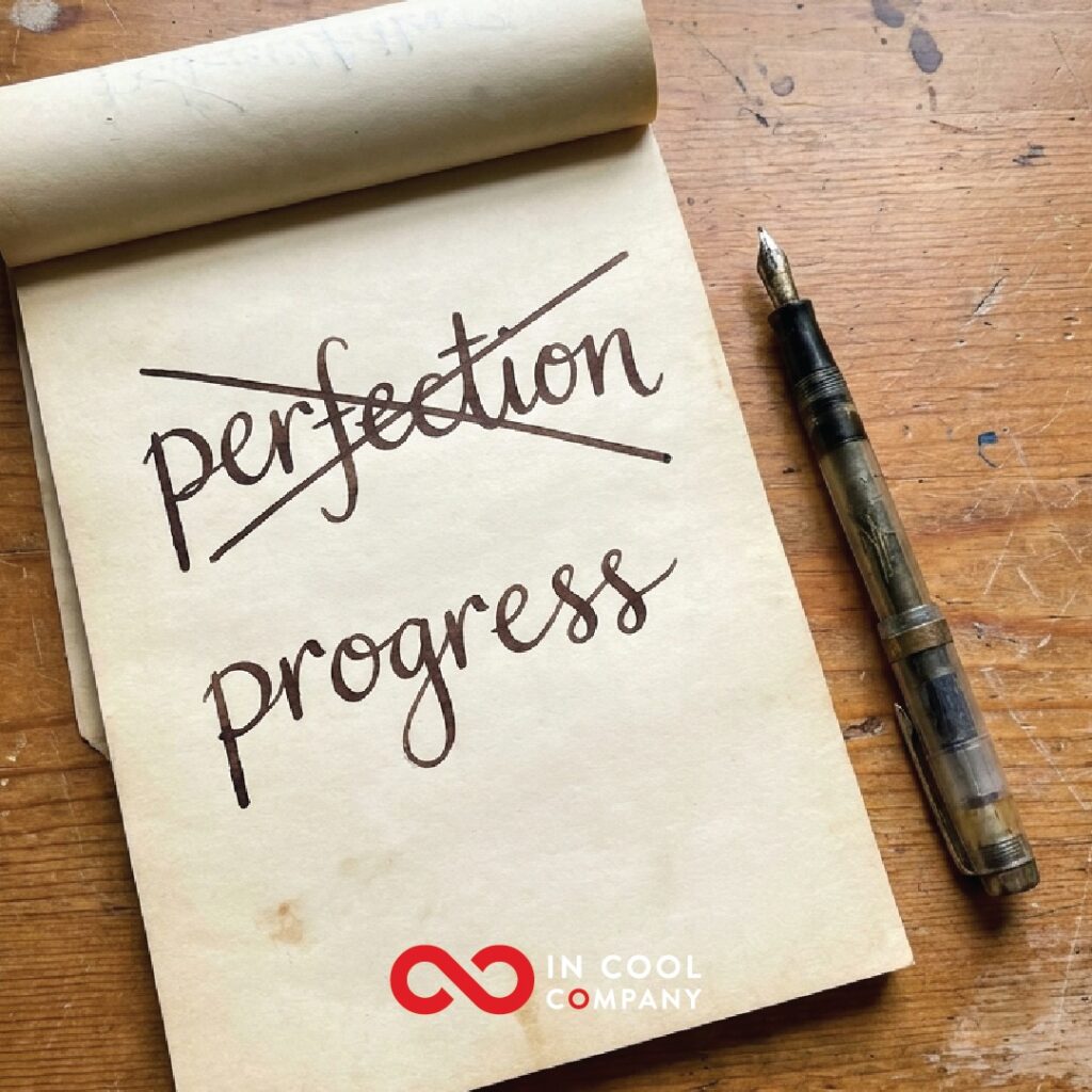 The word perfection is written on a notepad, but it is crossed out and below it is the word progress